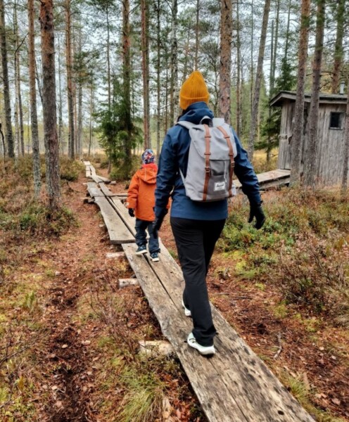 Lapsi ja aikuinen kulkevat metsässä pitkospuilla.