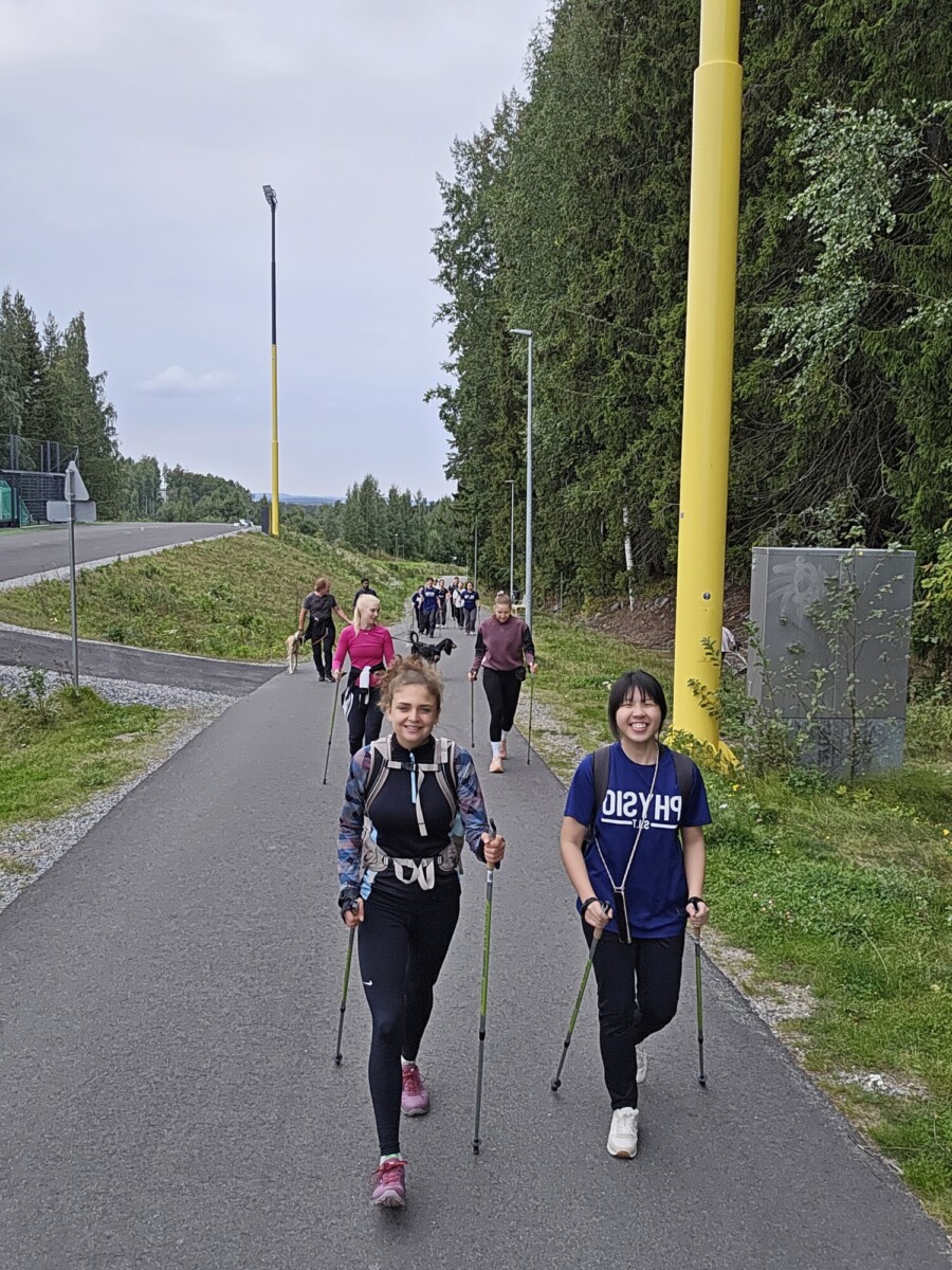 Ihmisiä sauvakävelemässä kadulla. 